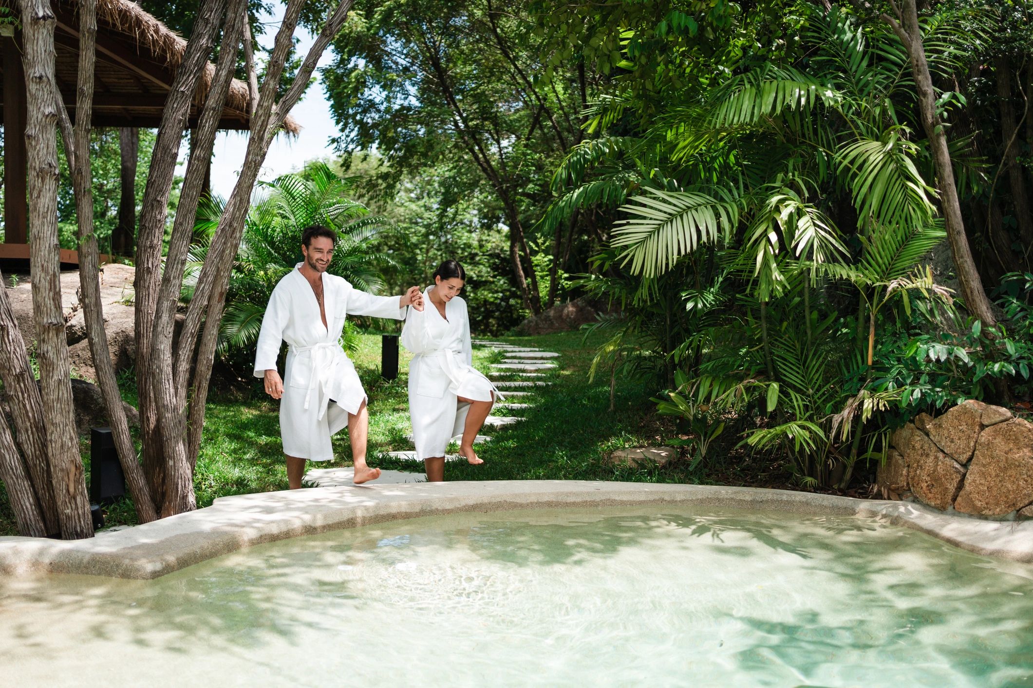 Couple on vacation walking toward a pool at a resort