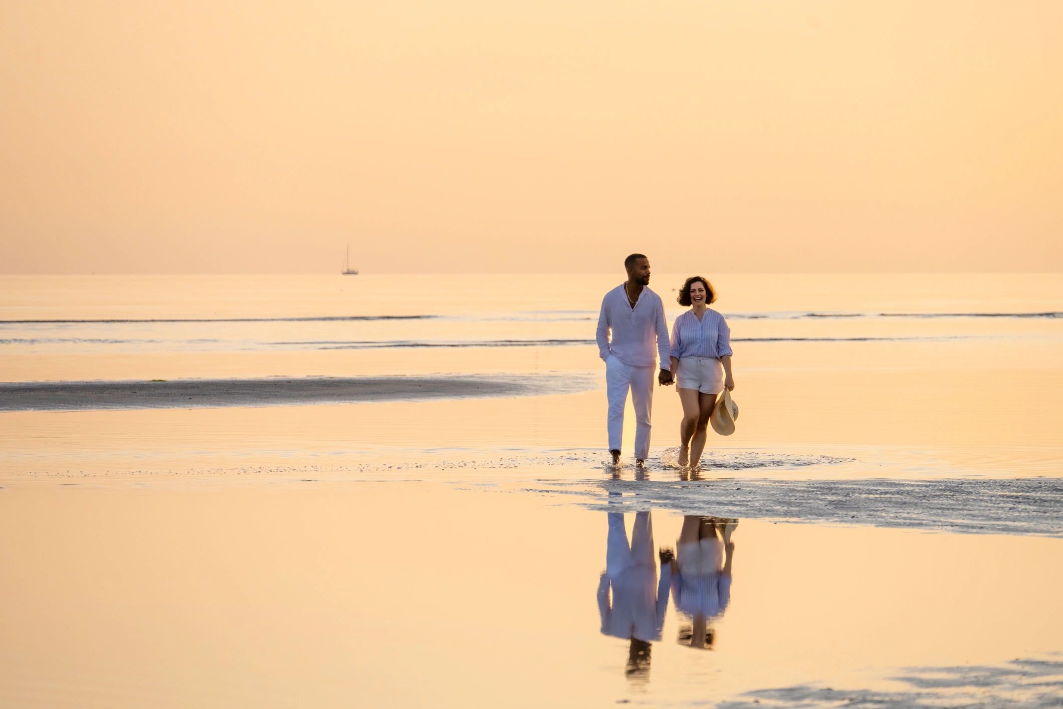 Couple walking along coastline at sunset